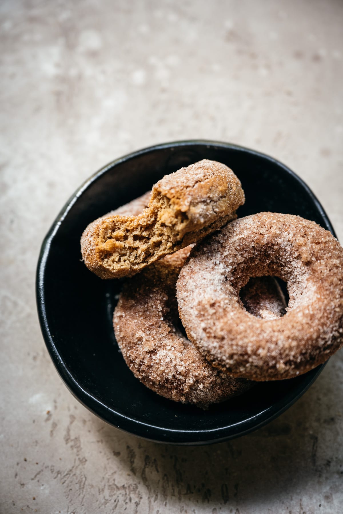 side view of a vegan baked apple cider donut with a bite taken out.
