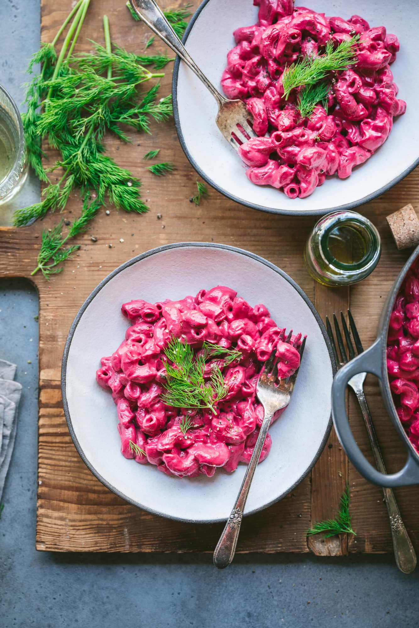 overhead view of two bowls of vegan beet pasta in white bowls with forks.