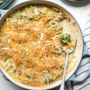 overhead view of cheesy vegan broccoli casserole topped with breadcrumbs in large skillet.