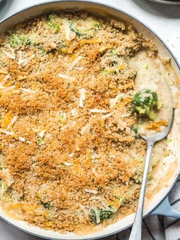 overhead view of cheesy vegan broccoli casserole topped with breadcrumbs in large skillet.