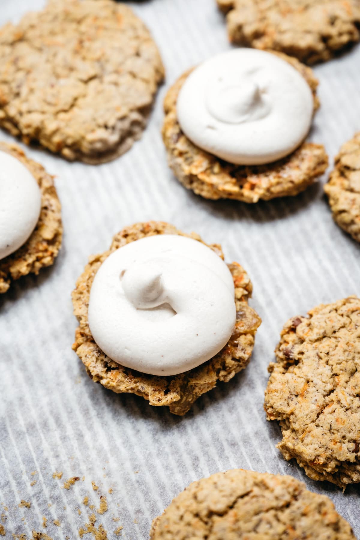 close up photo of vegan carrot cake cookie with cream cheese frosting on top.
