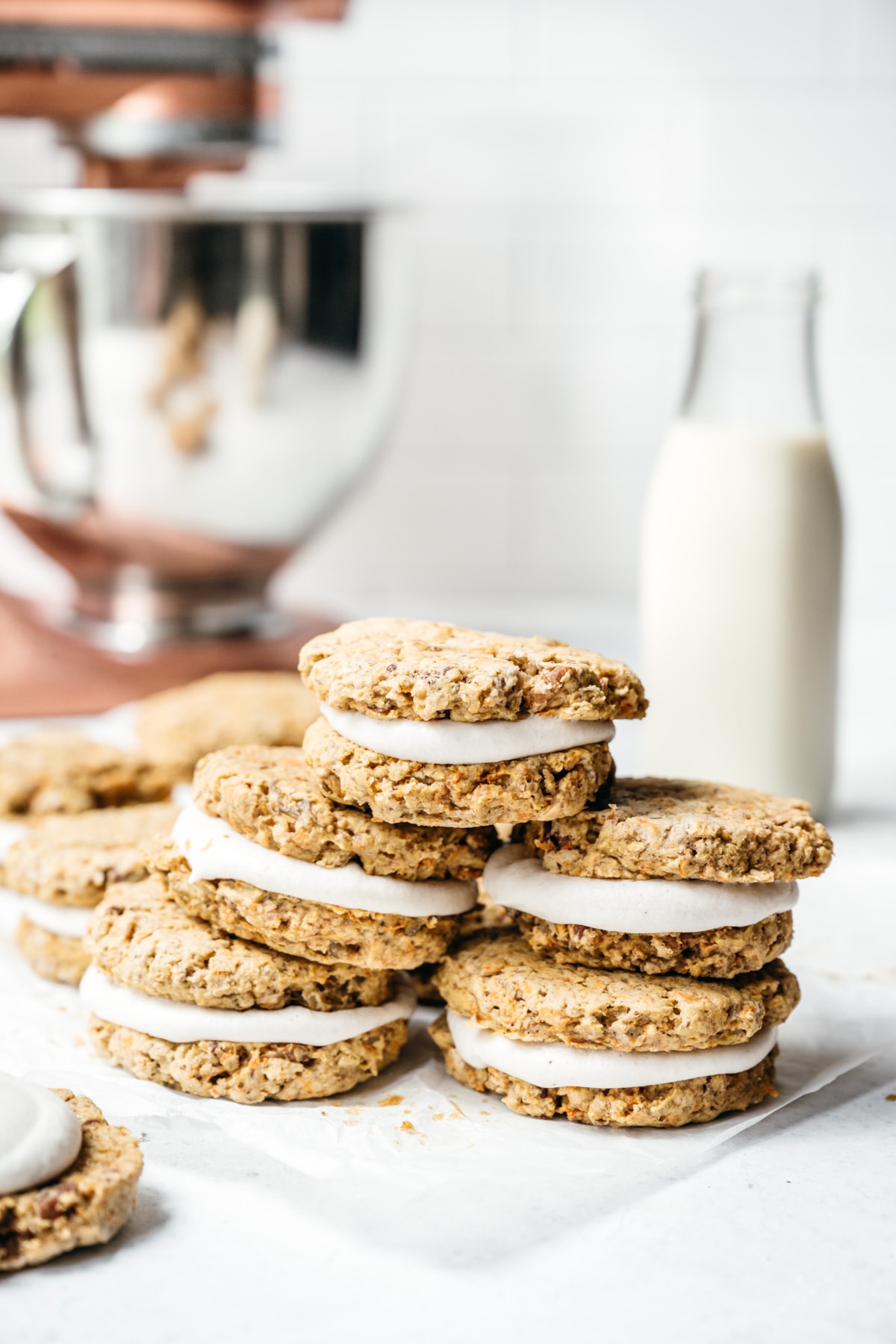 side view of stack of carrot cake sandwich cookies with cream cheese frosting.