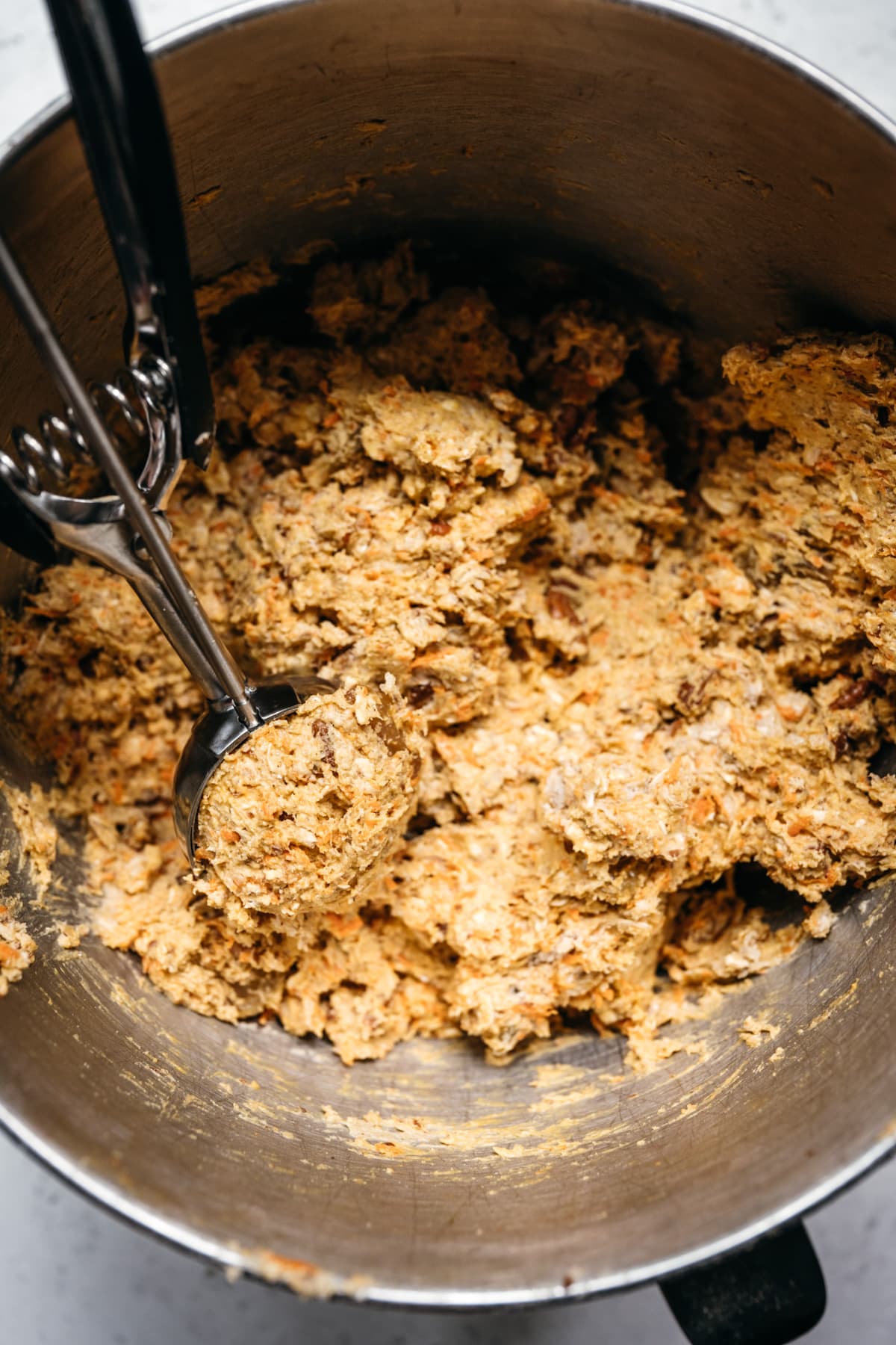 close up view of carrot cake cookie dough in mixing bowl.