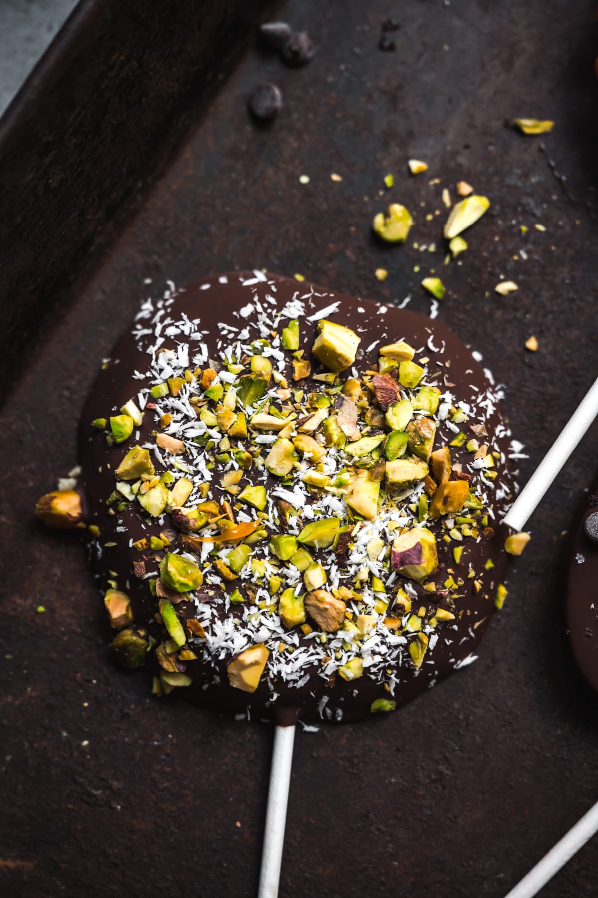 overhead view of chocolate covered apple slice with coconut and pistachios.