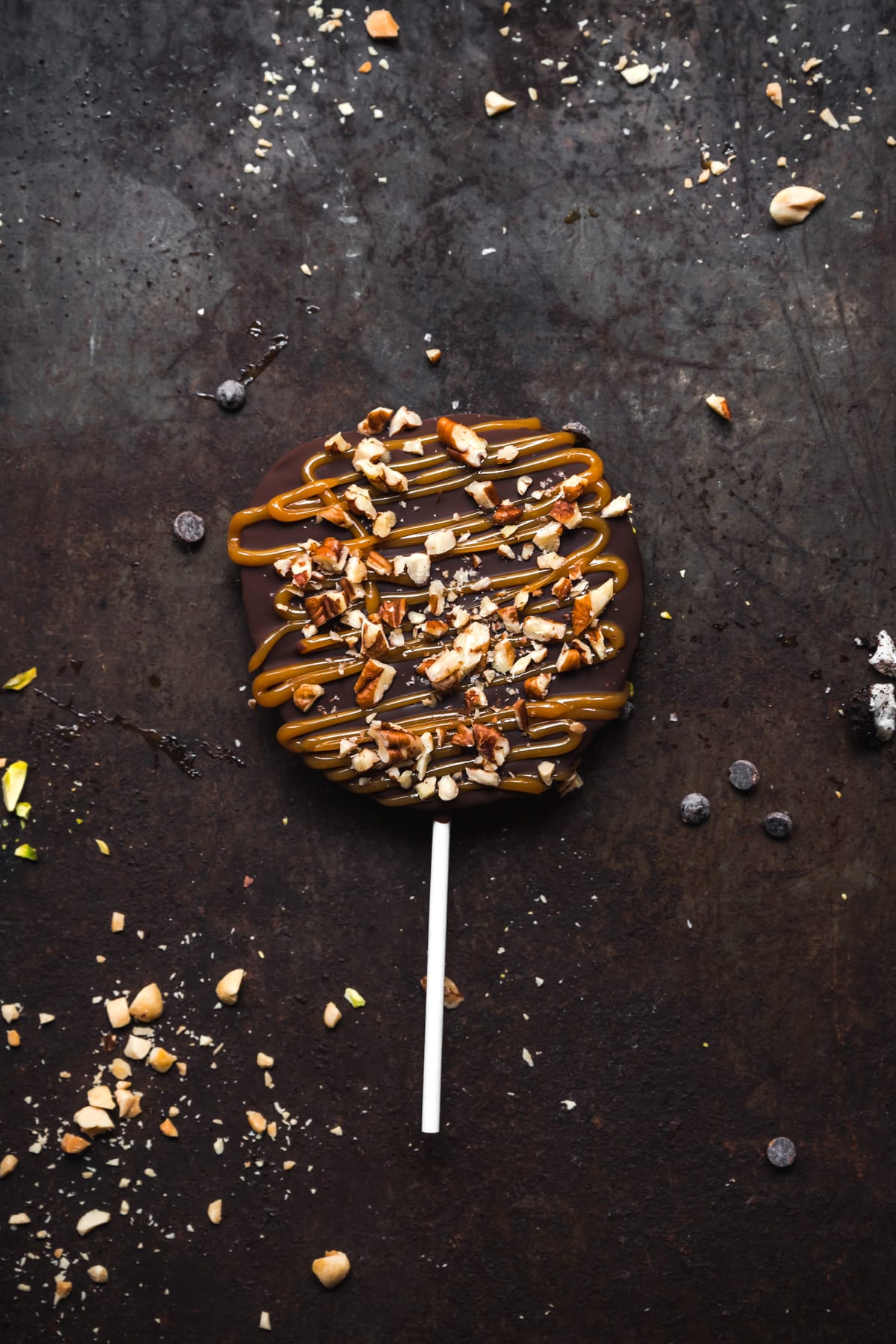 close up view of chocolate covered apple slice with caramel and pecans. 