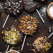 overhead view of chocolate covered apple slices with various toppings on rustic sheet pan.