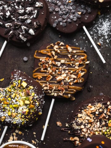 overhead view of chocolate covered apple slices with various toppings on rustic sheet pan.