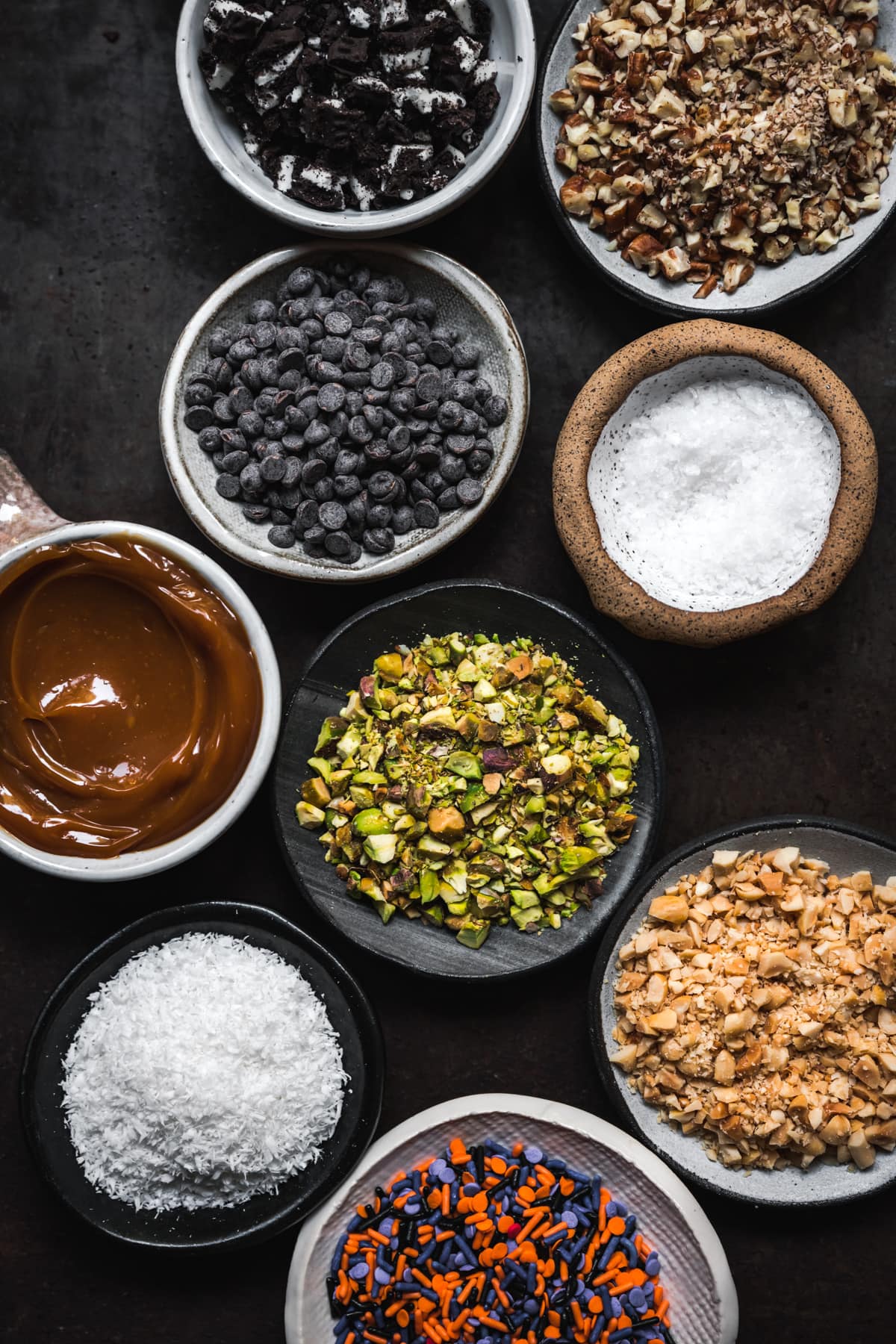 overhead view of toppings for chocolate covered apples in small bowls.