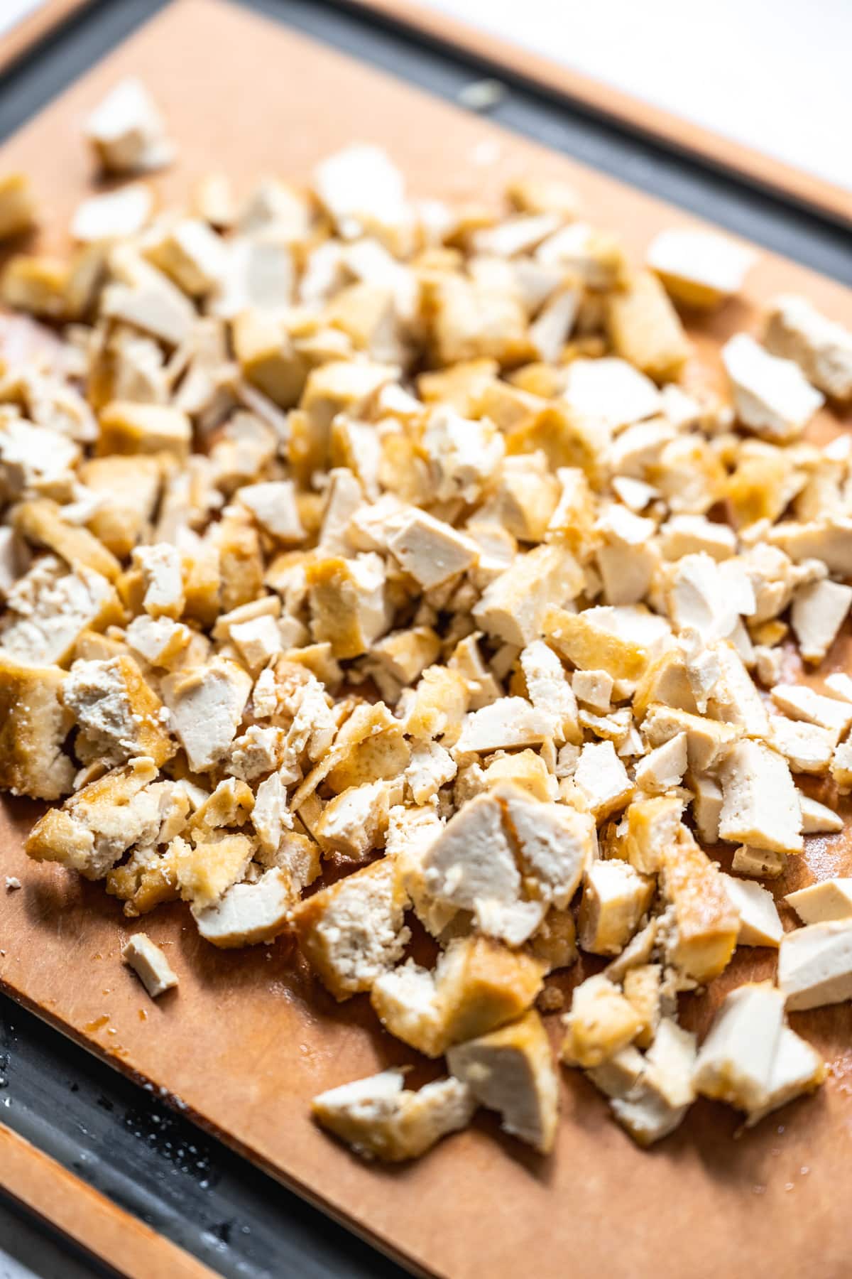 close up view of chopped, crispy tofu on a cutting board.