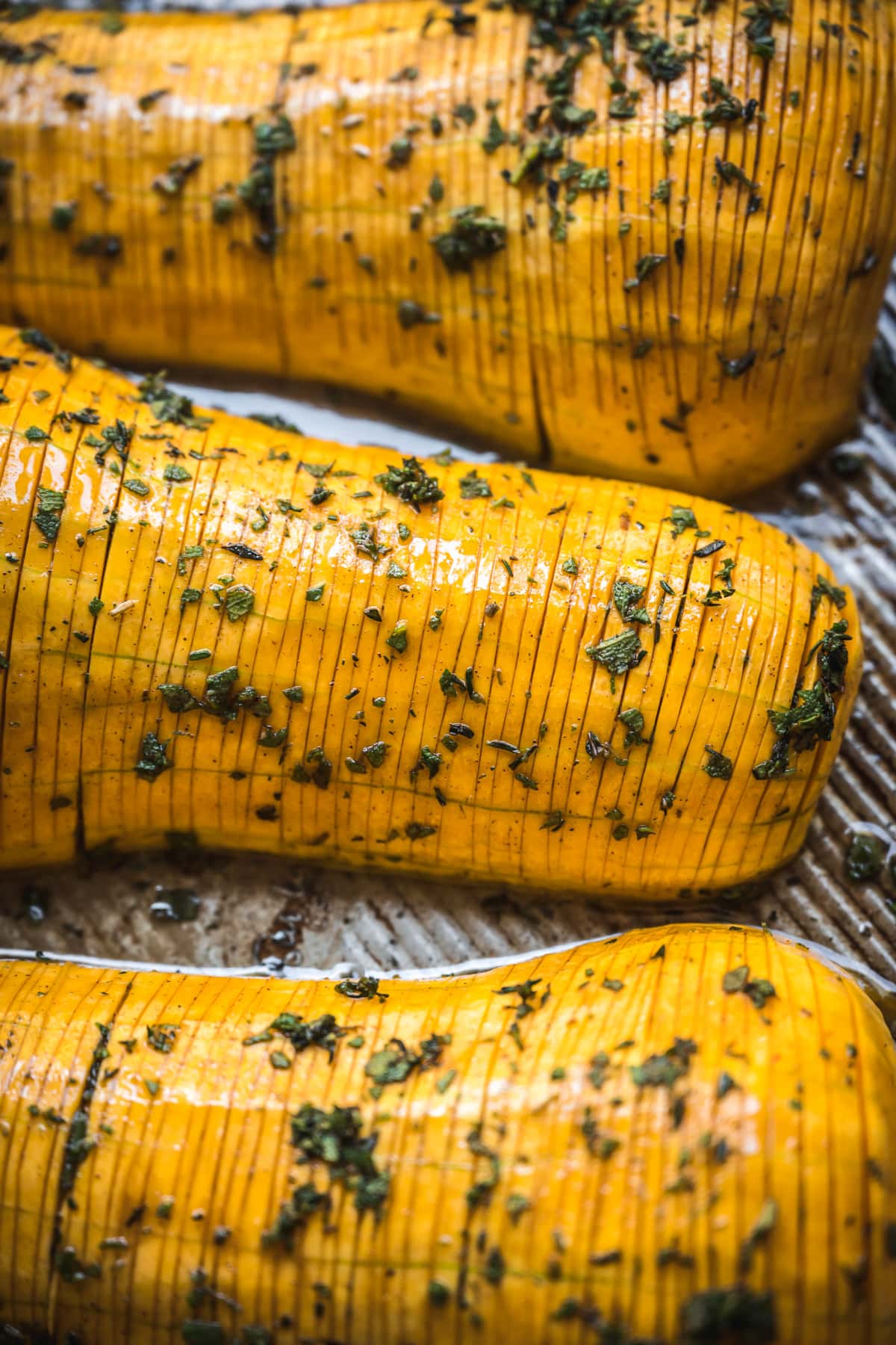 close up view of butternut squash hasselbacked on sheet pan.