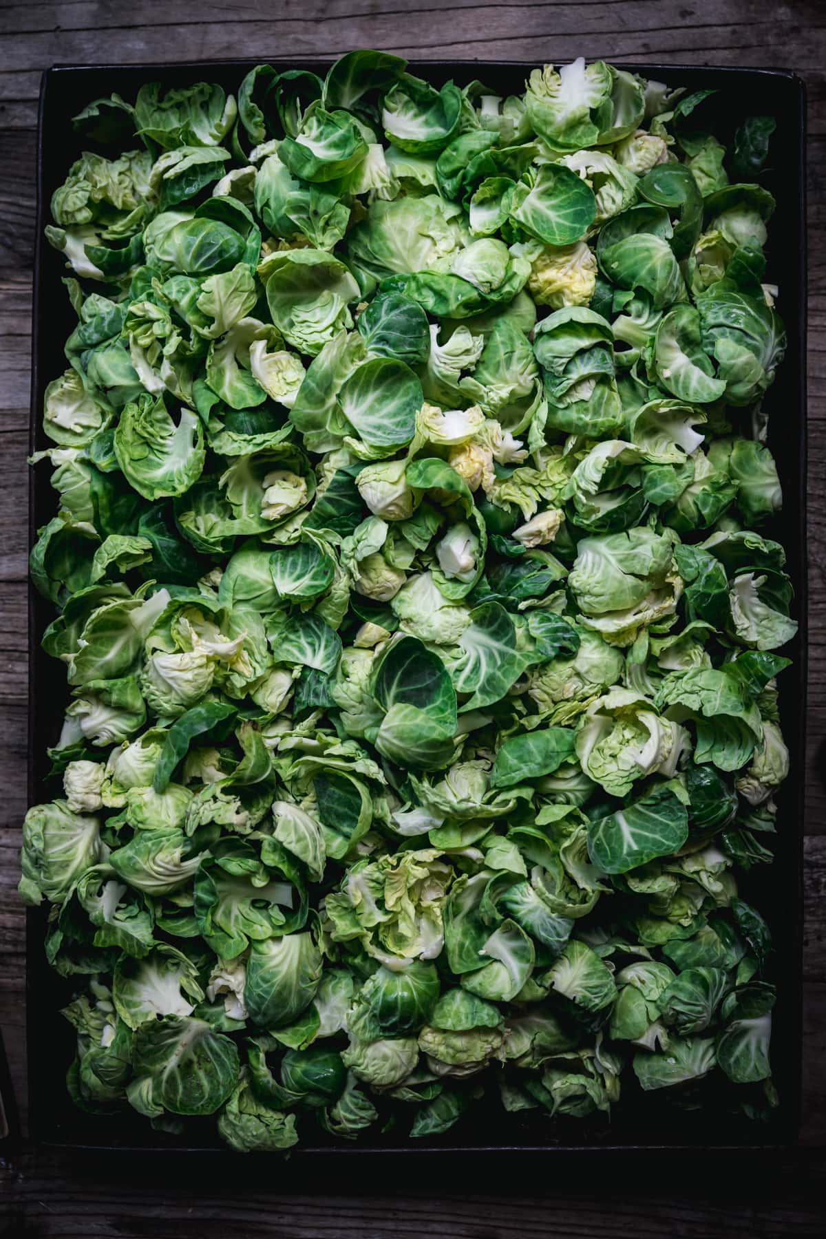 overhead view of raw brussels sprout leaves in a large pan.