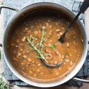 close up overhead view of vegan mushroom gravy in a pot garnished with fresh rosemary.