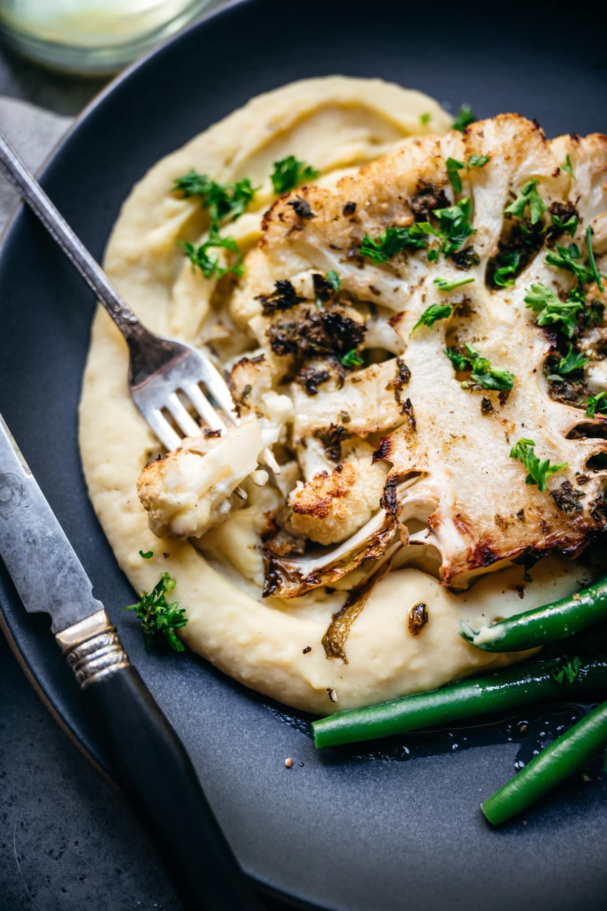 close up view of cauliflower steak with mashed potatoes. 