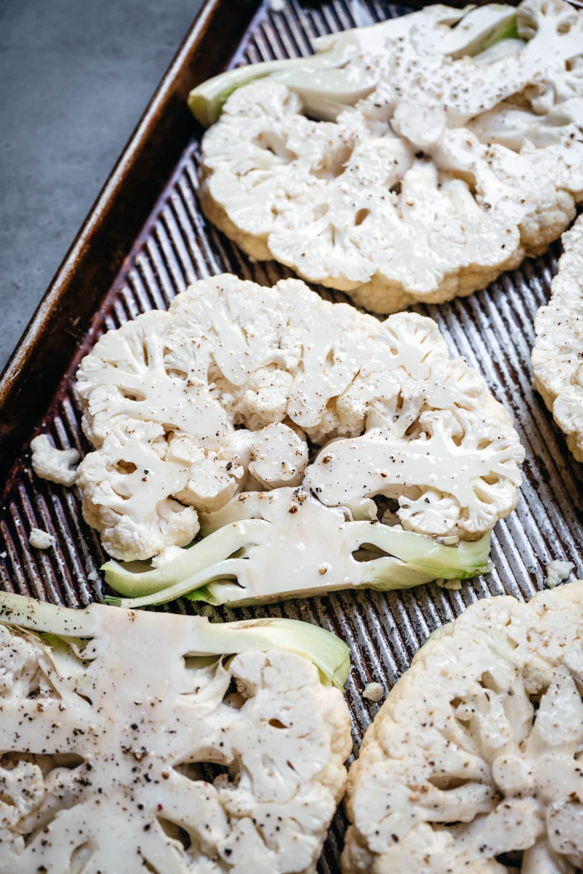 close up view of cauliflower steaks before roasting on sheet pan. 