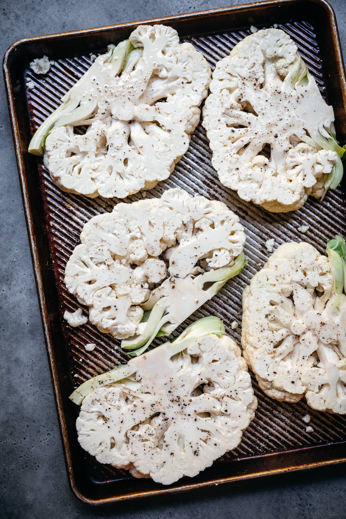 overhead view of cauliflower steaks before roasting on sheet pan. 