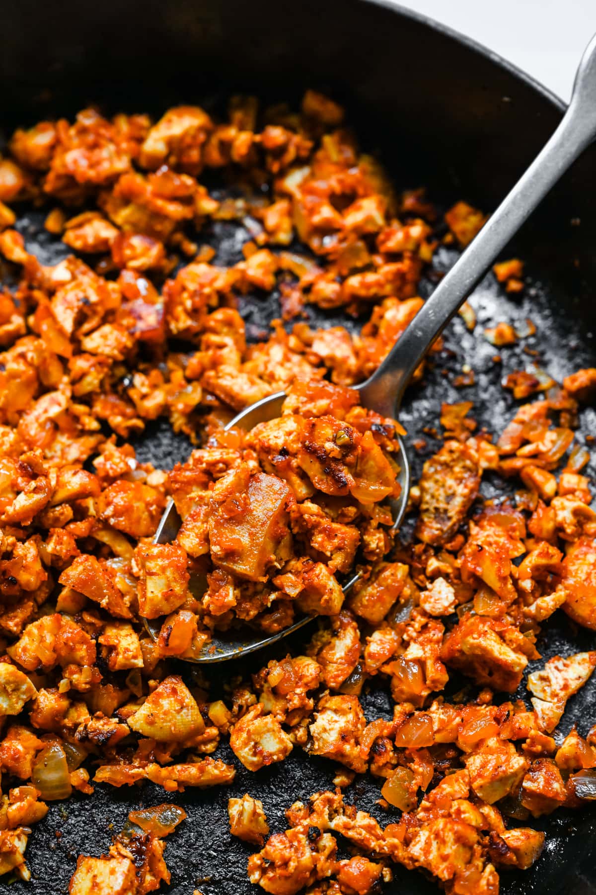 Close up view of sofritas tofu in a skillet with a serving spoon.