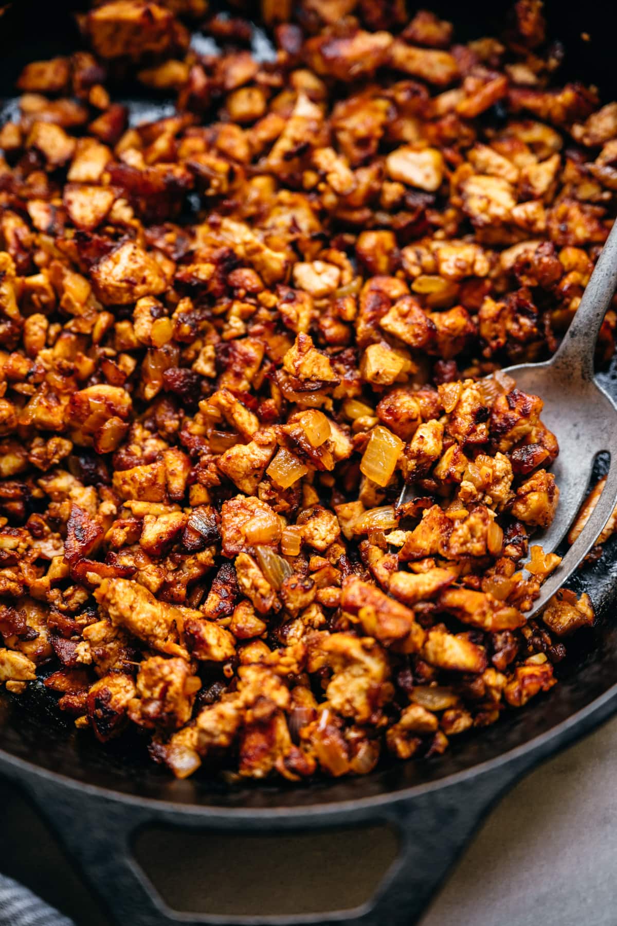 close up view of crispy sofritas tofu in a cast iron skillet.