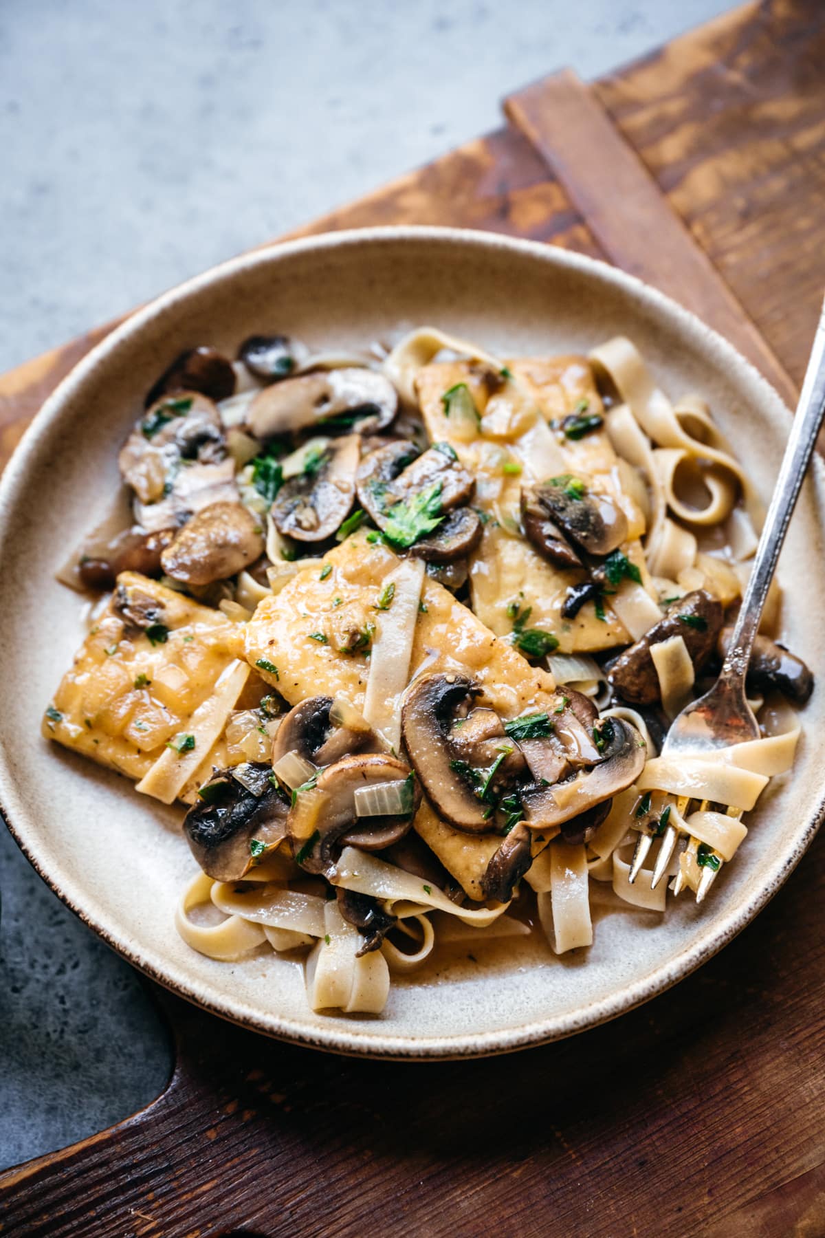 side view of tofu marsala in a bowl with pasta. 