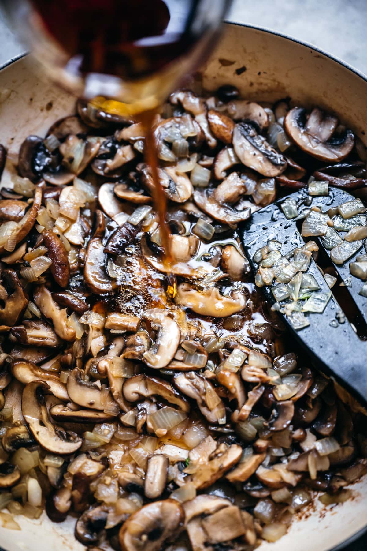 pouring marsala wine into mushroom sauce. 