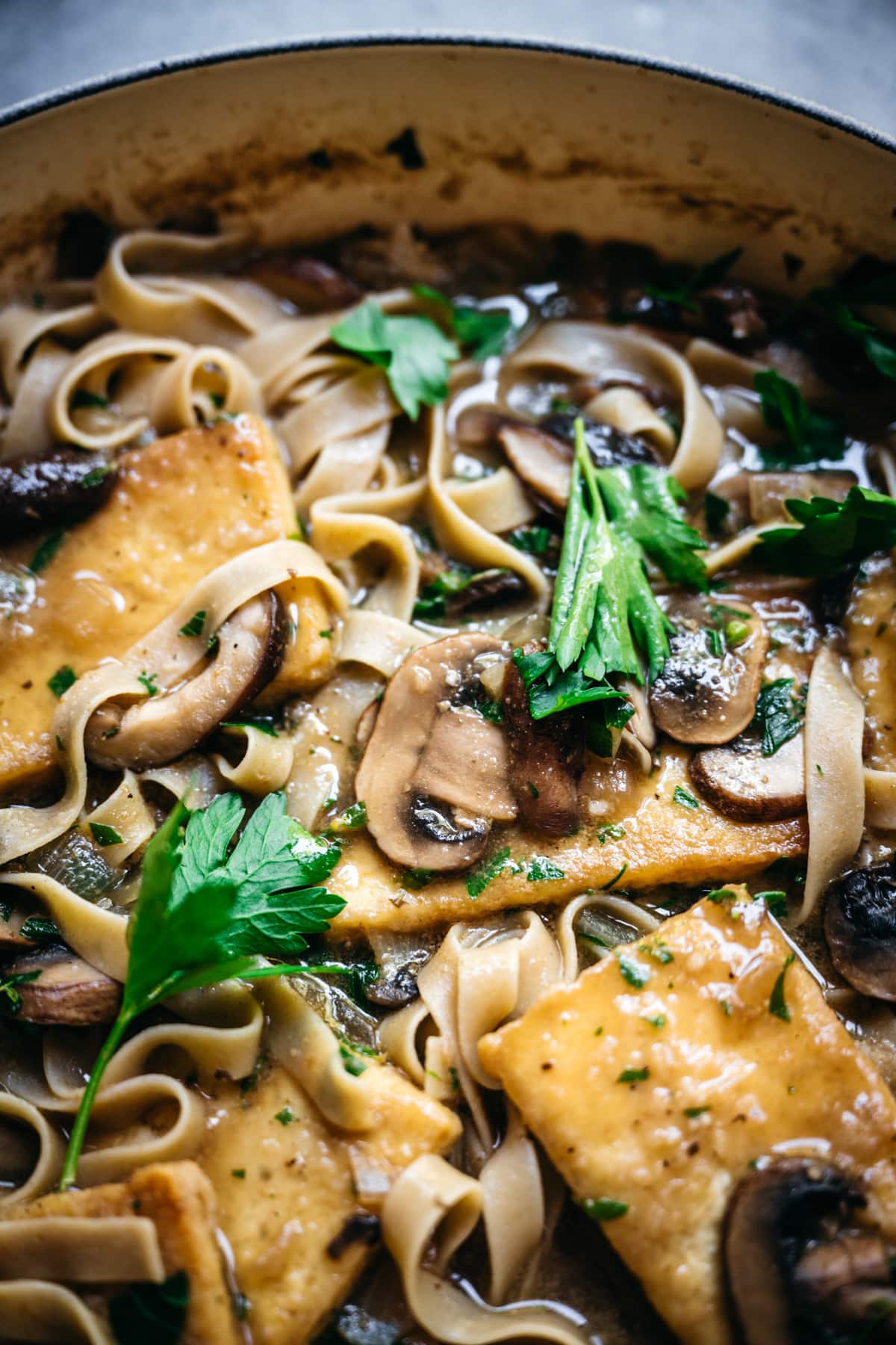 close up view of a mushroom in a pan of tofu marsala.