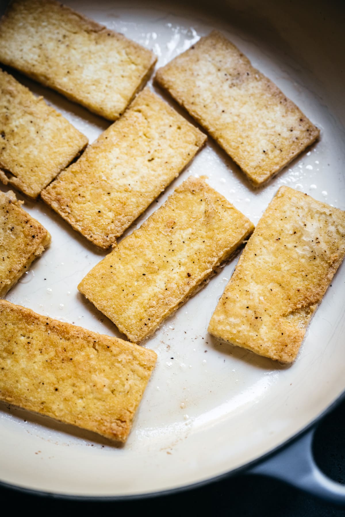 close up view of pan-fried tofu cutlets in a pan.