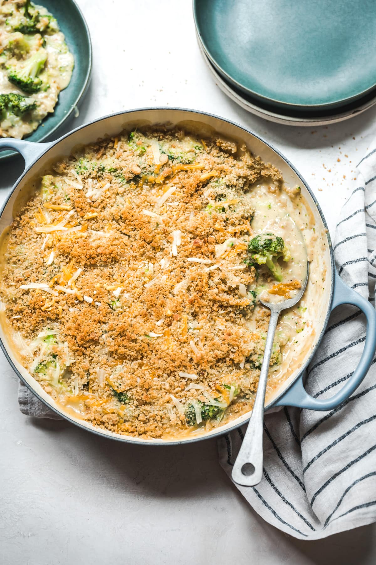 overhead view of cheesy vegan broccoli casserole topped with breadcrumbs in large skillet.