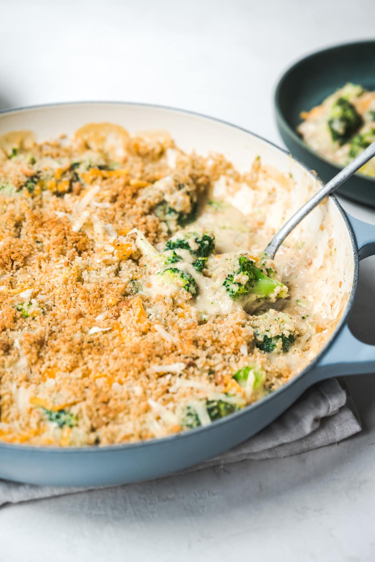 close up side view of vegan broccoli casserole with a serving spoon.