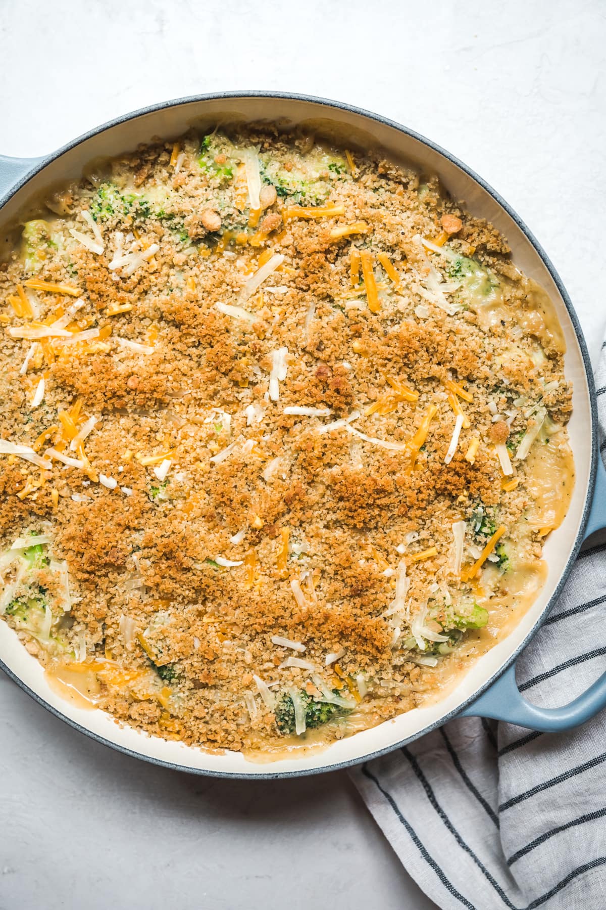 overhead view of cheesy vegan broccoli casserole topped with breadcrumbs in large skillet.