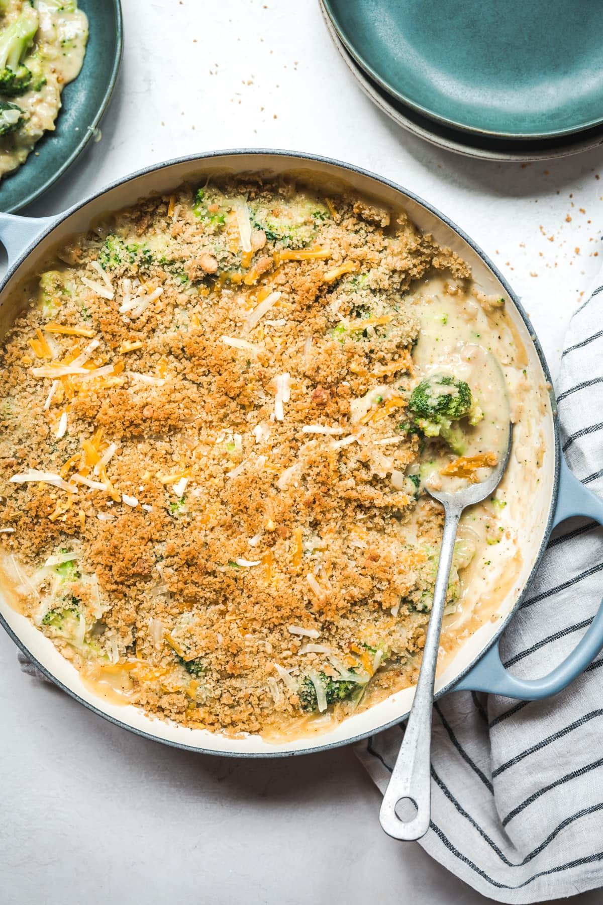 overhead view of cheesy vegan broccoli casserole topped with breadcrumbs in large skillet.