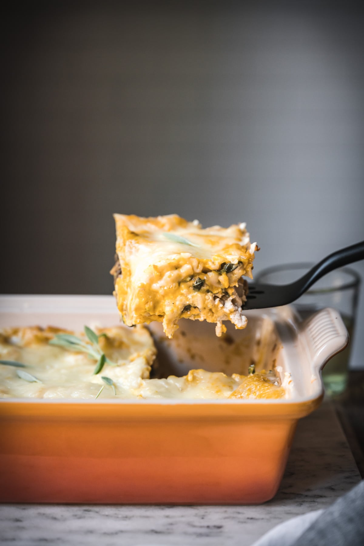 side view of spatula holding up slice of vegan butternut squash lasagna.