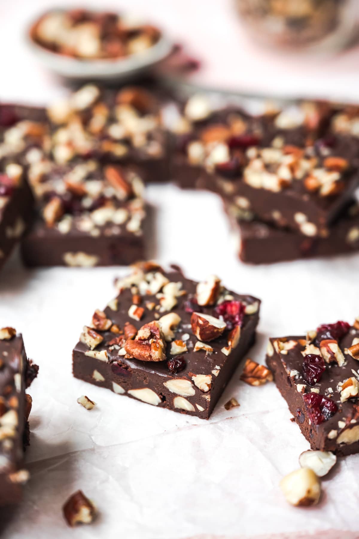 side view of a square of vegan fudge with nuts and cranberries. 