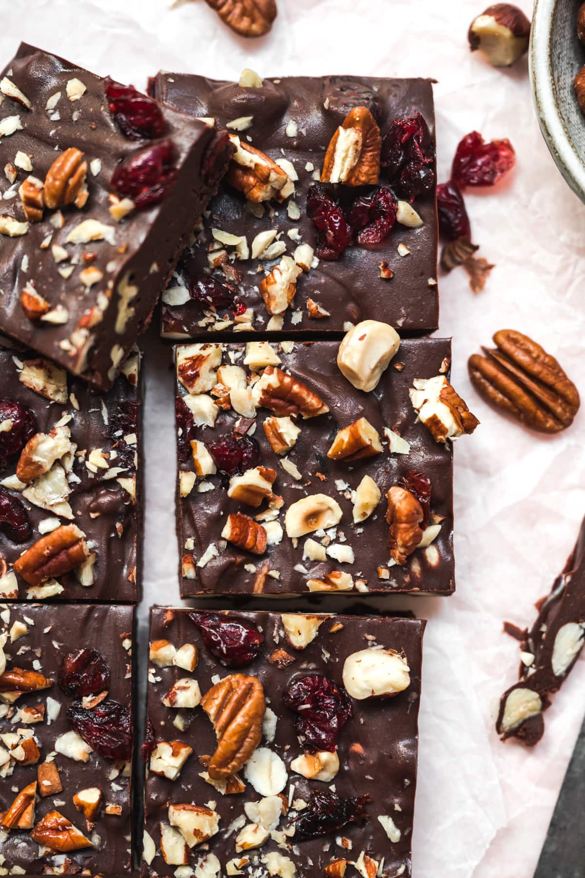 close up overhead view of vegan cranberry nut fudge sliced into squares on parchment paper. 