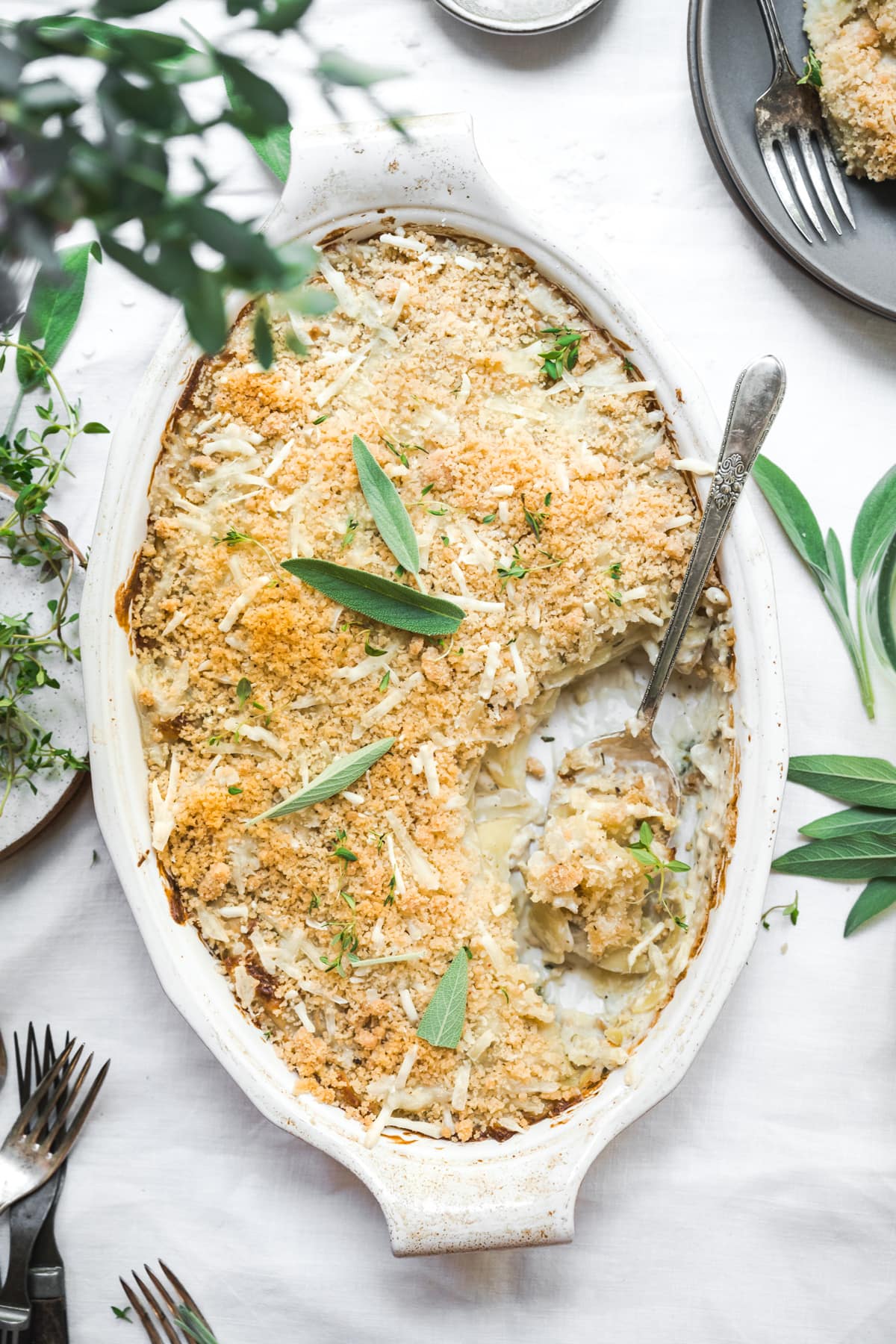 overhead view of vegan scalloped potatoes with breadcrumb topping in a casserole dish on white linen tablecloth.