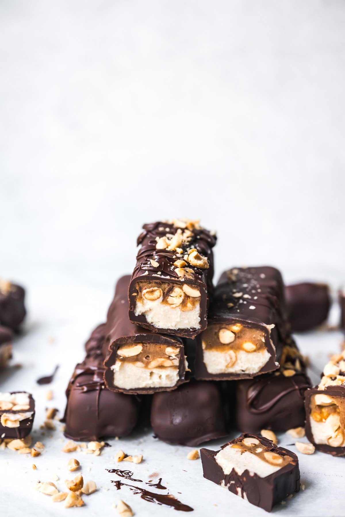 Stack of homemade vegan snickers bars covered in chocolate.