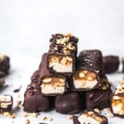 Stack of homemade vegan snickers bars covered in chocolate.