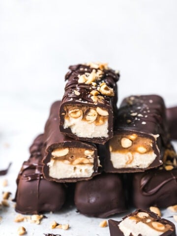 Stack of homemade vegan snickers bars covered in chocolate.