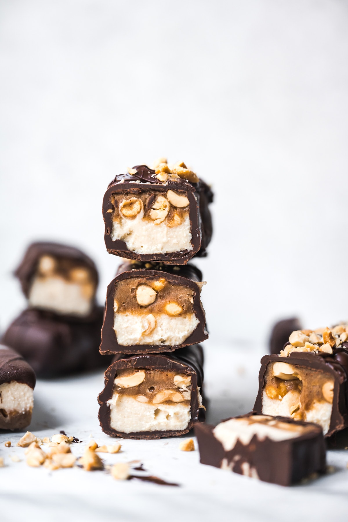 Stack of homemade vegan snickers bars covered in chocolate. 