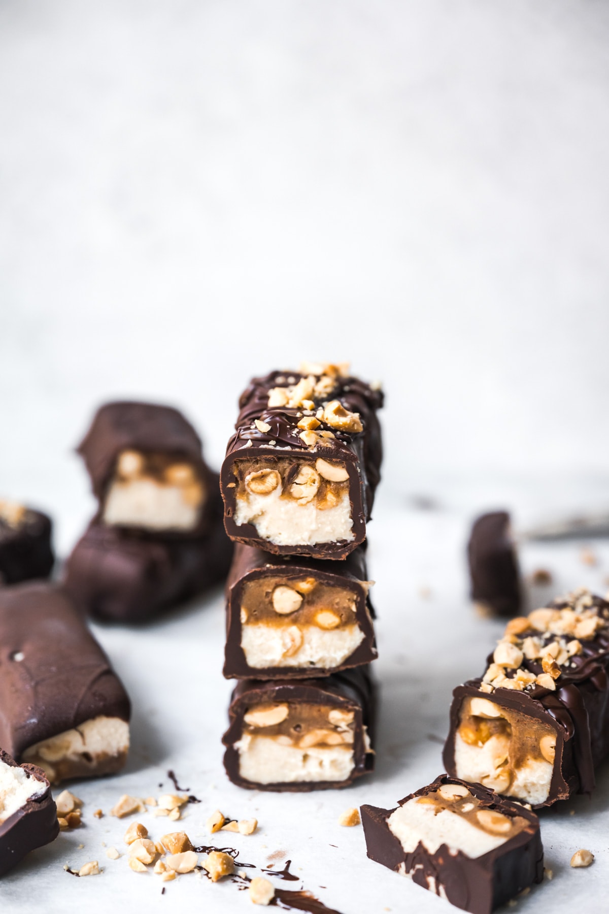 Stack of homemade vegan snickers bars covered in chocolate. 