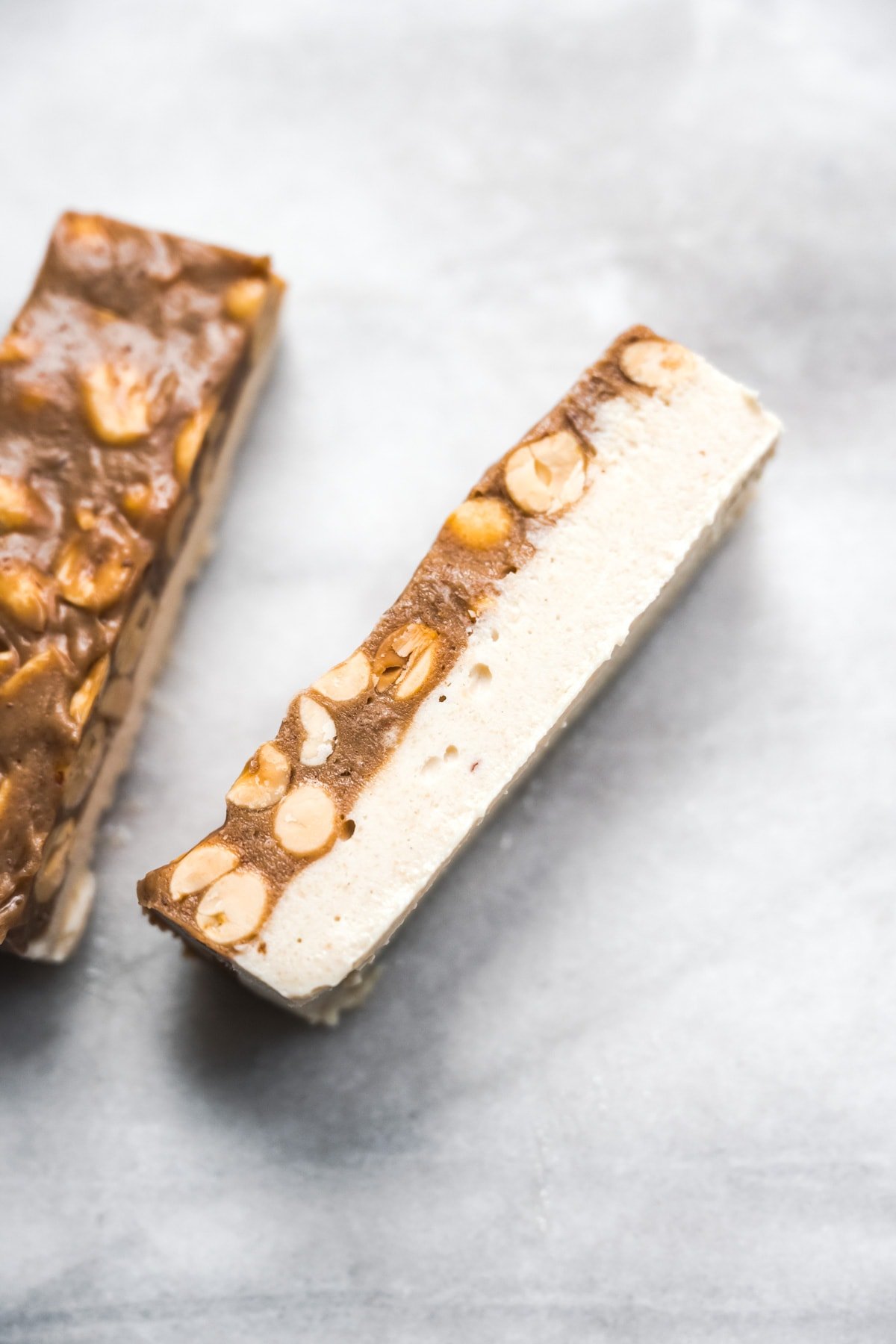 close up view of homemade vegan snickers bars with nougat and caramel layer. 