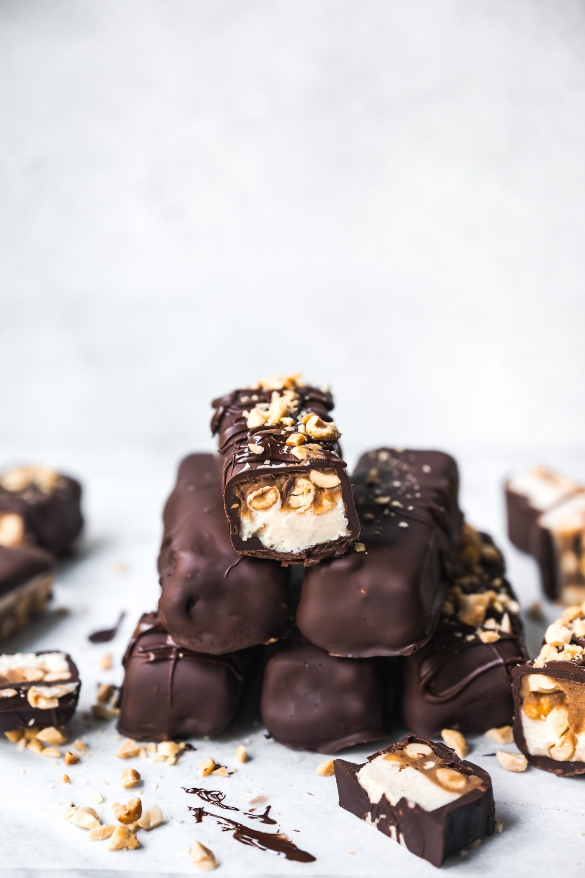 Stack of homemade vegan snickers bars covered in chocolate. 