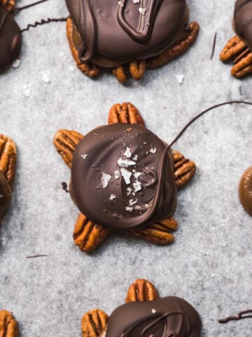 overhead view of vegan chocolate caramel pecan turtles on parchment paper.