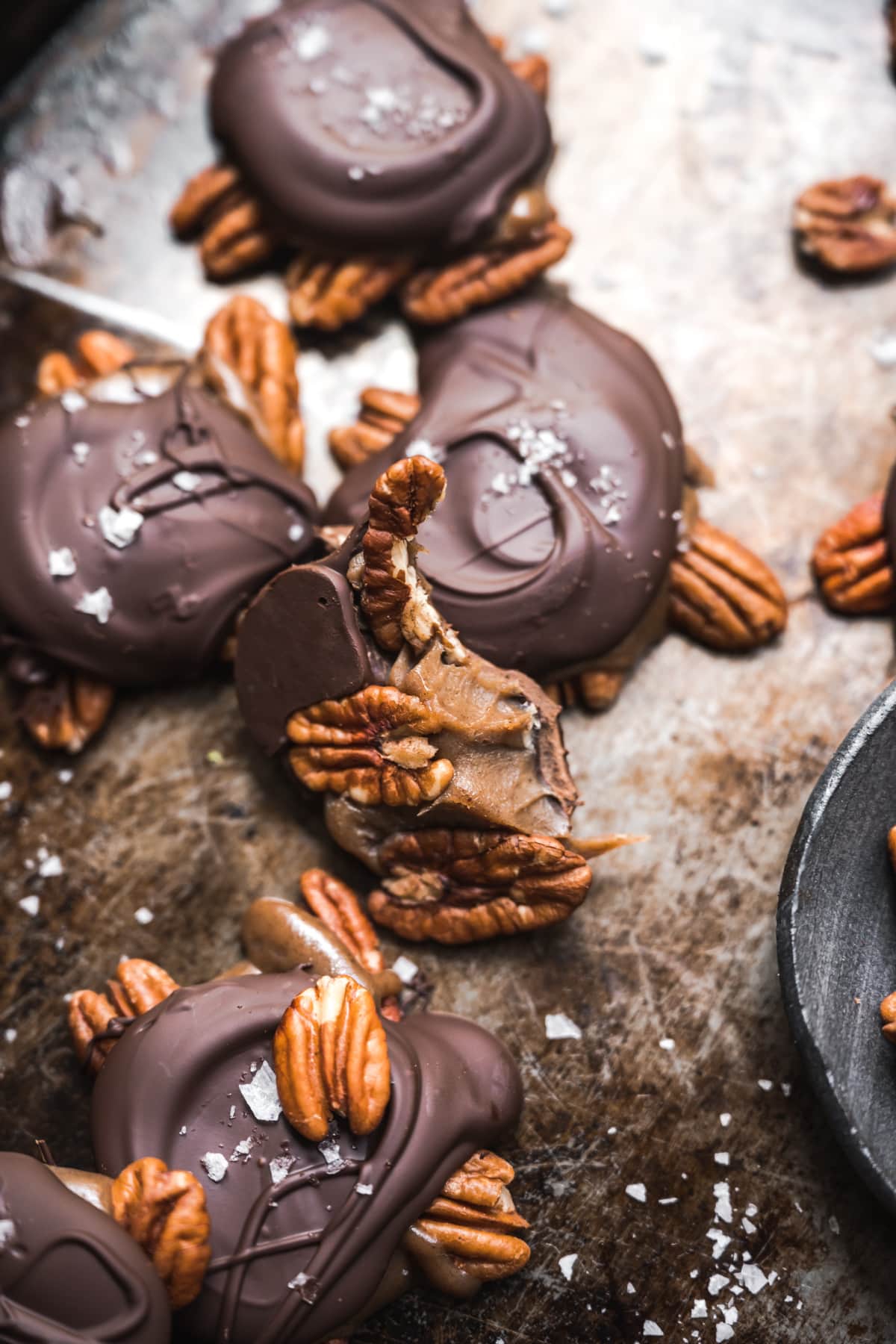 close up view of pecan caramel chocolate turtle with bite taken out.