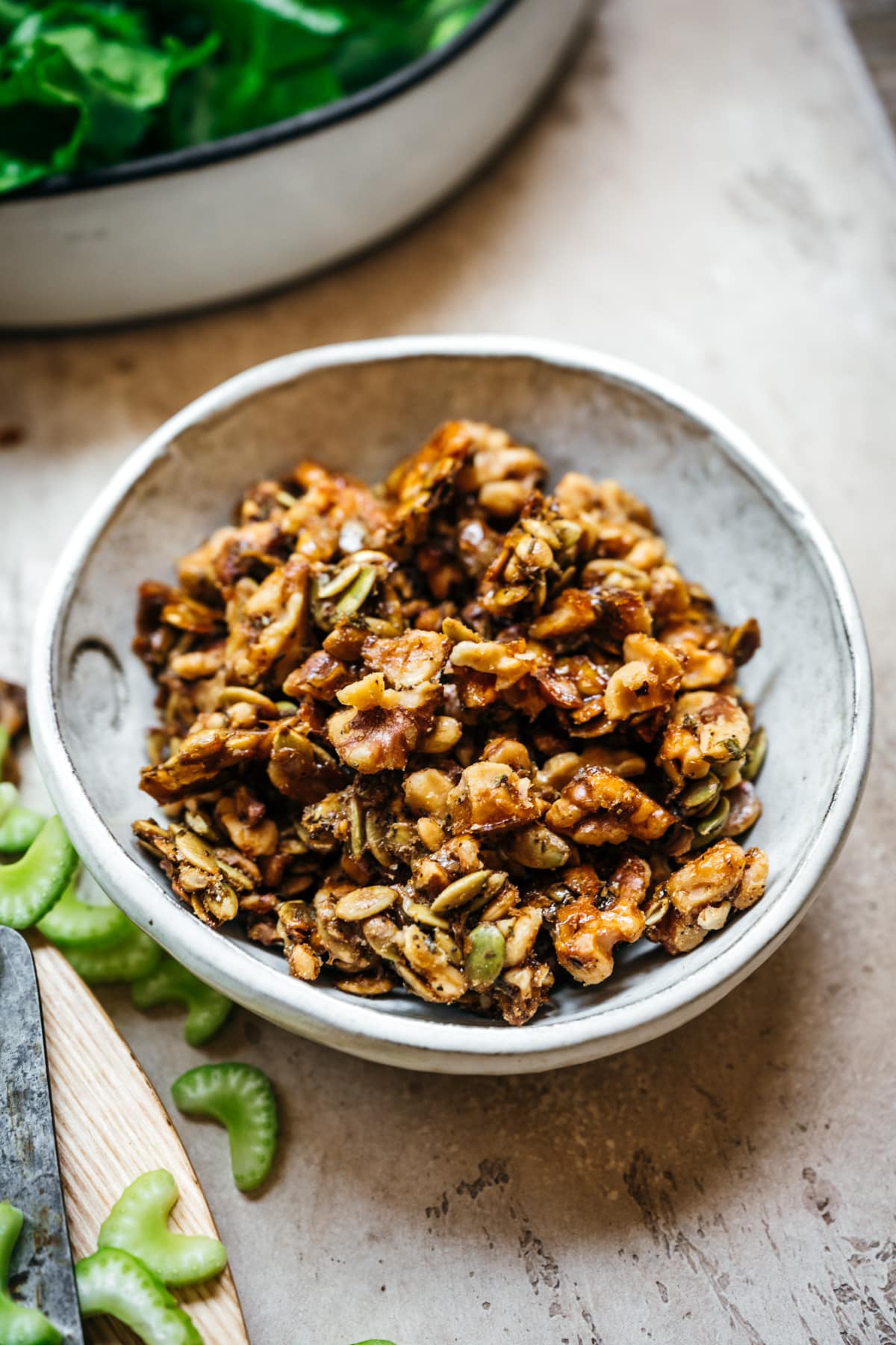 close up view of walnut pumpkin seed brittle in a small white bowl.