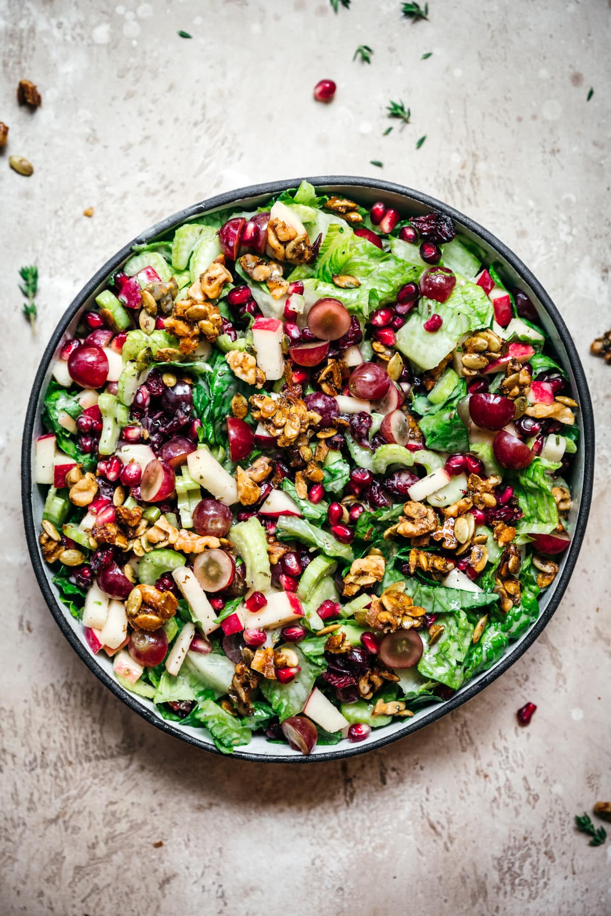 overhead view of vegan waldorf salad with walnut brittle and pomegranate in a bowl.