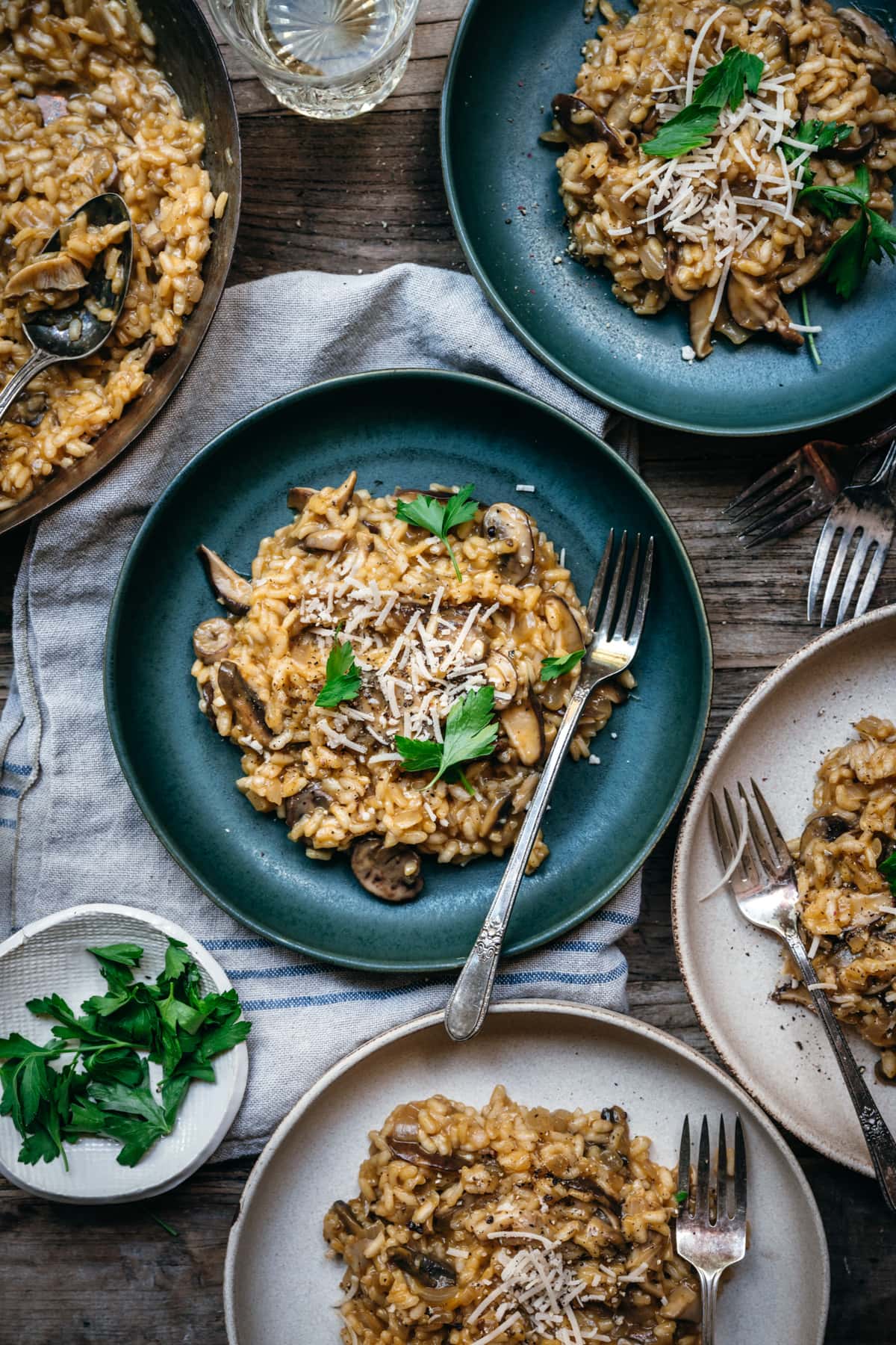 overhead view of multiple bowls of vegan mushroom risotto with glasses of white wine.