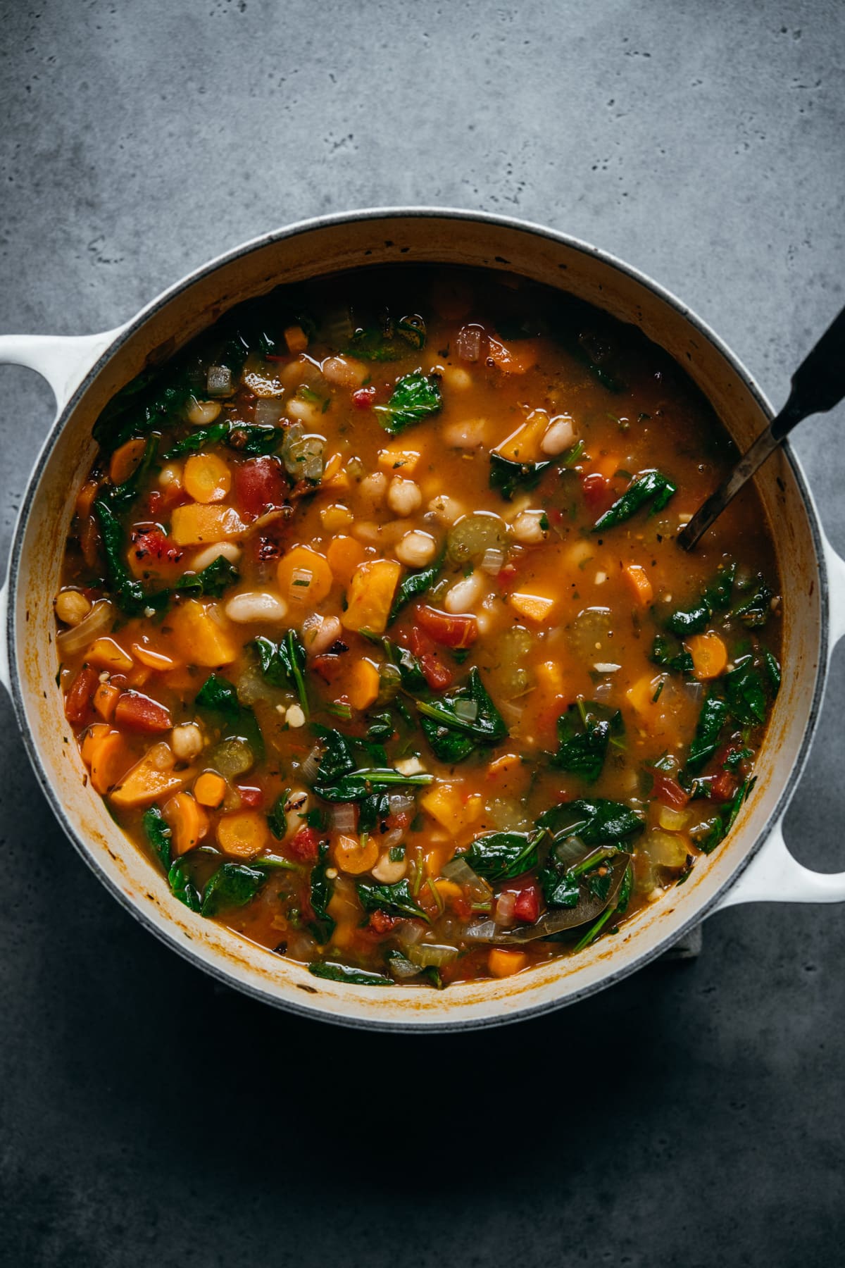 overhead view of vegan bean vegetable soup in white pot.