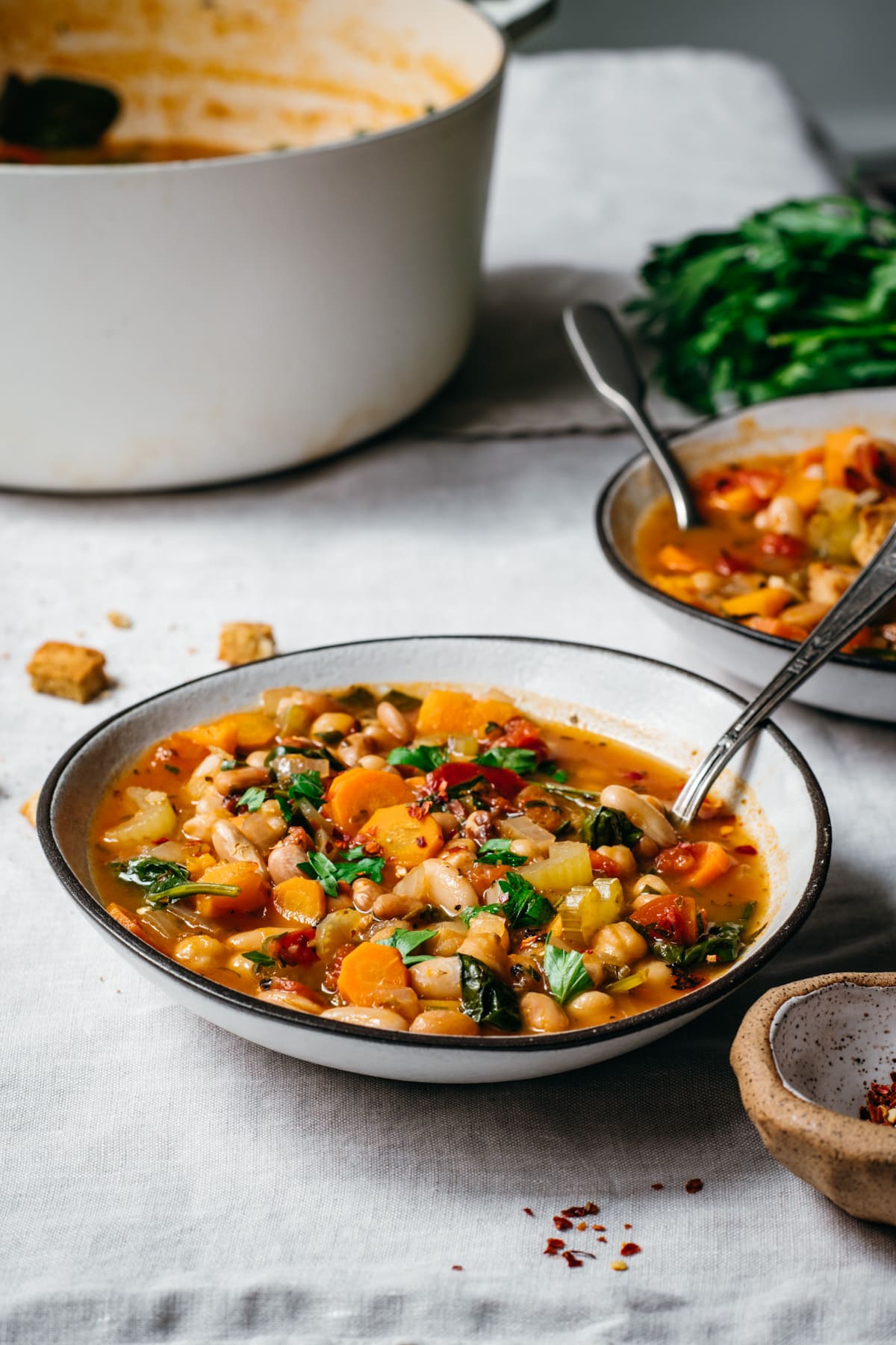 side view of vegan bean soup on white tablecloth. 