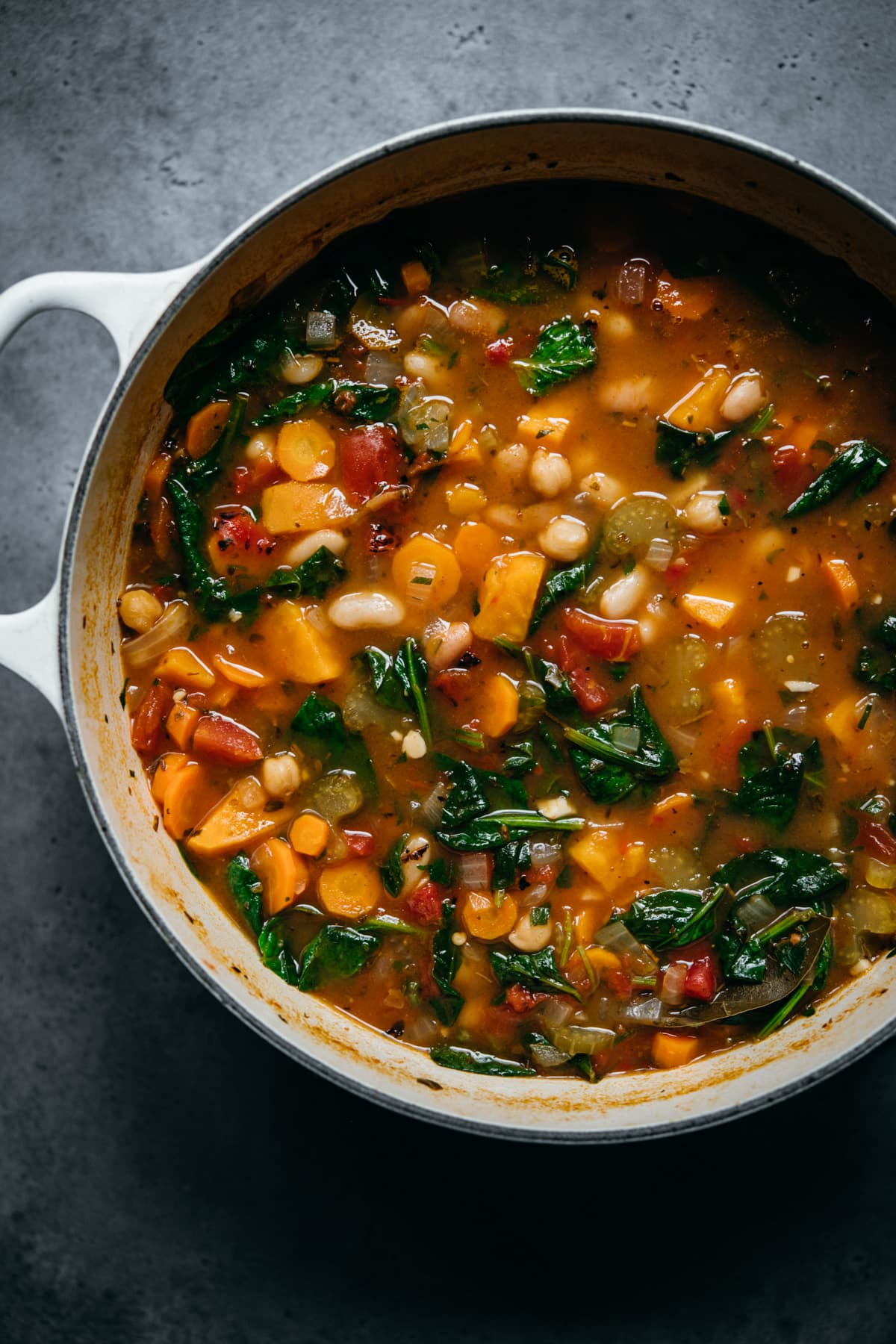 overhead view of vegan bean vegetable soup in white pot.