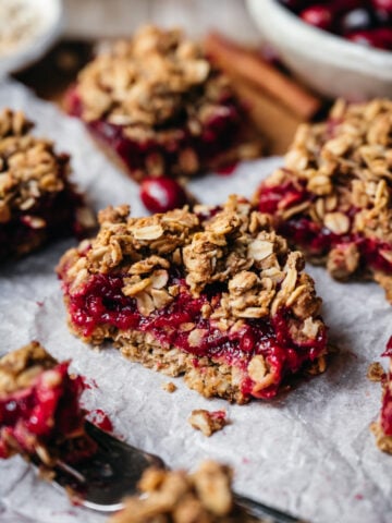 side view of vegan cranberry crumb bar cut in half with oat streusel topping.