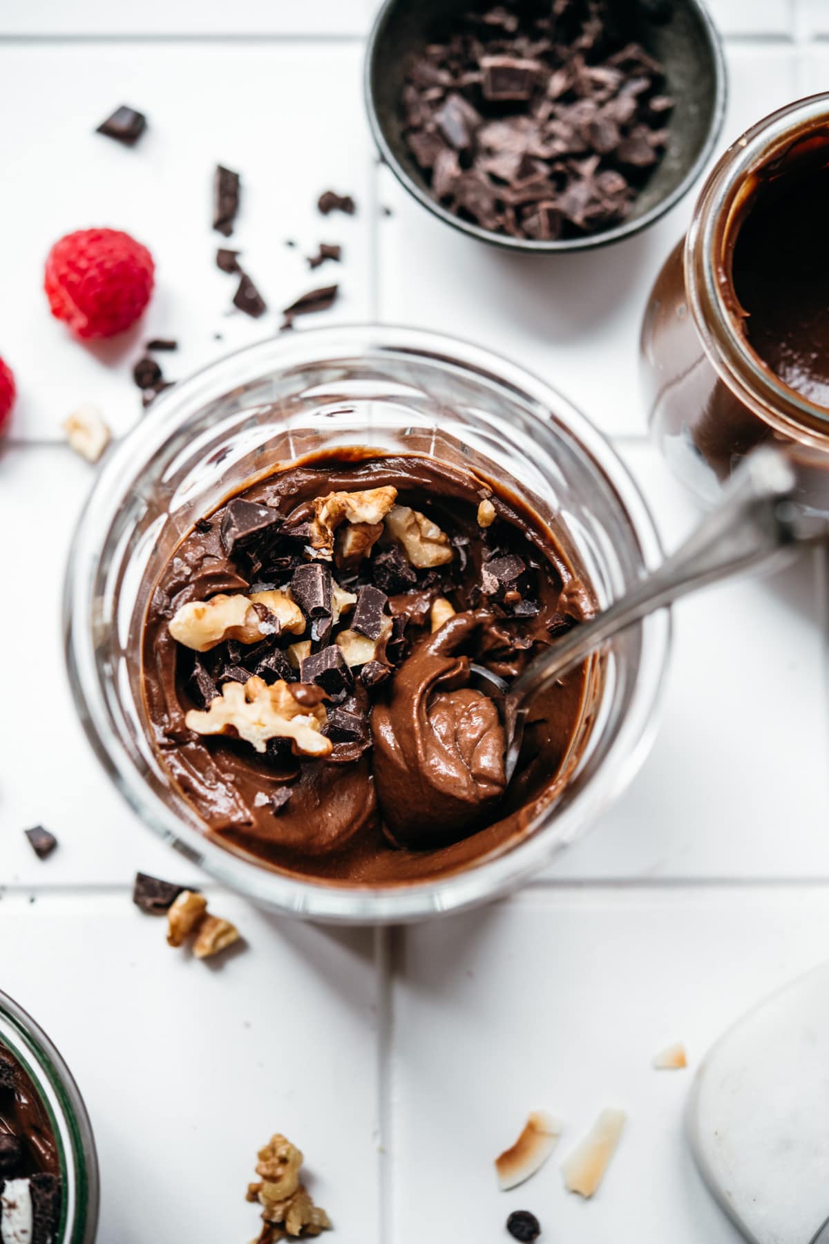 close up view of vegan chocolate mousse in a jar with nuts.